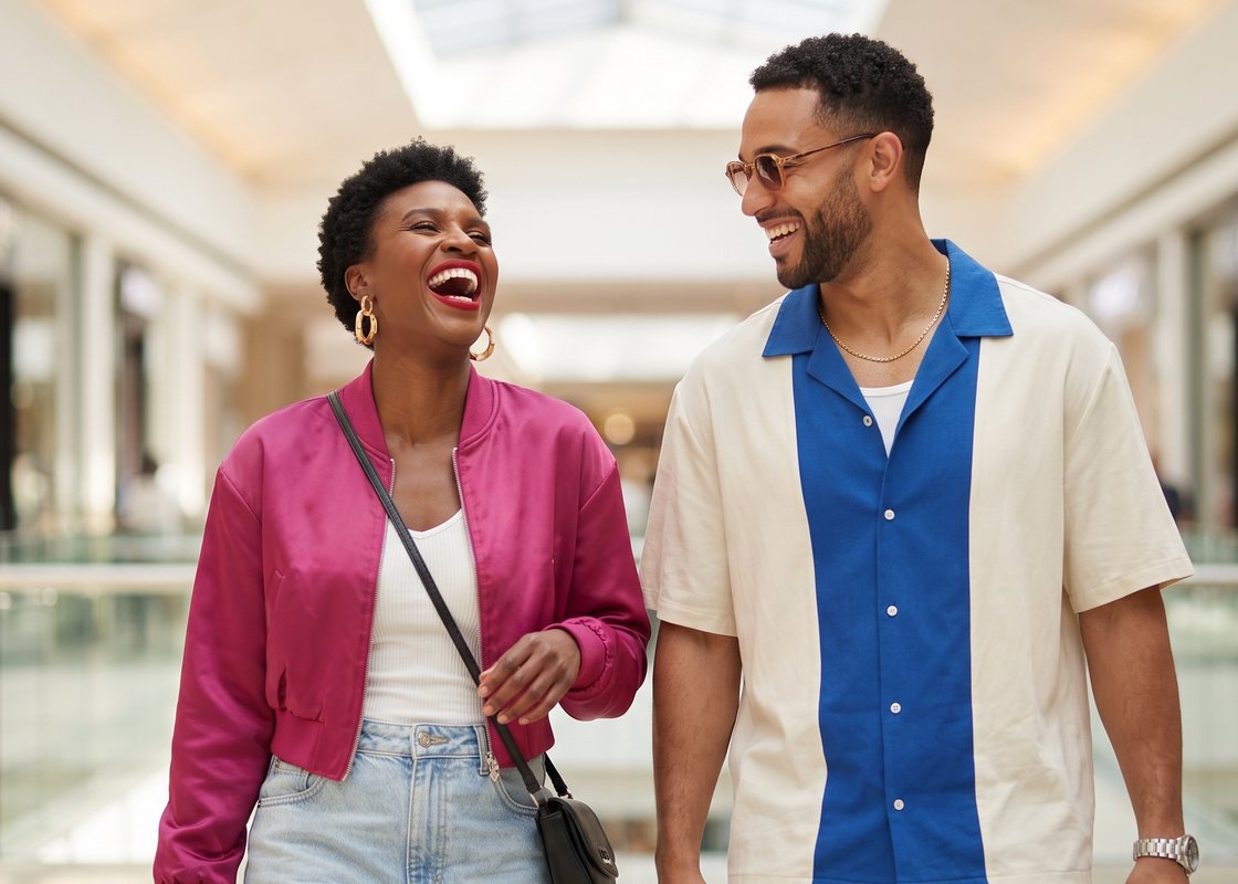 A couple laughing as they walk through a mall